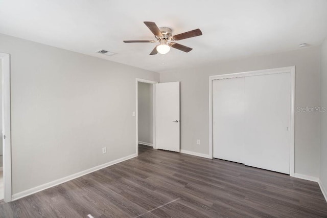 unfurnished bedroom featuring dark hardwood / wood-style flooring, ceiling fan, and a closet