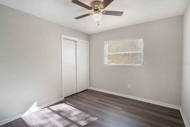 unfurnished bedroom with dark hardwood / wood-style flooring, a closet, and ceiling fan