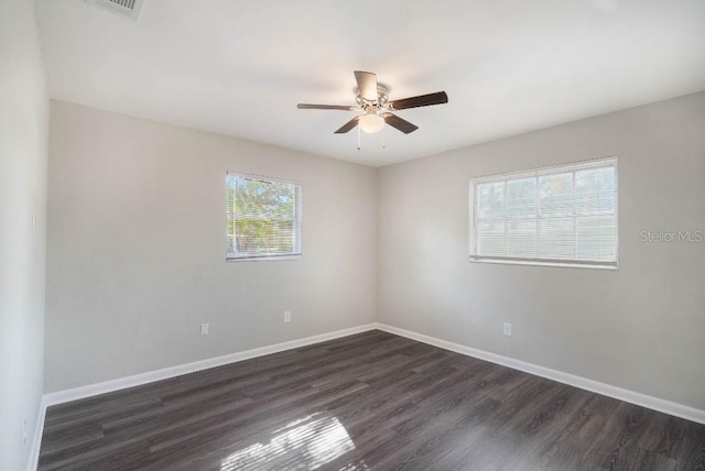 spare room featuring ceiling fan, a healthy amount of sunlight, and dark hardwood / wood-style floors