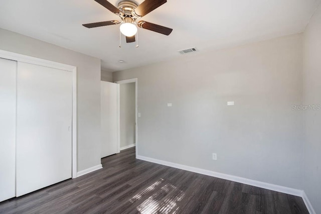 unfurnished bedroom featuring dark wood-type flooring, ceiling fan, and a closet