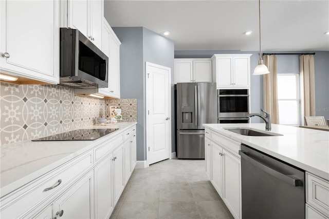 kitchen with decorative light fixtures, sink, white cabinets, stainless steel appliances, and light stone countertops