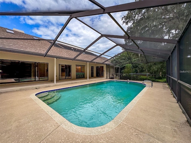 view of pool with glass enclosure and a patio area