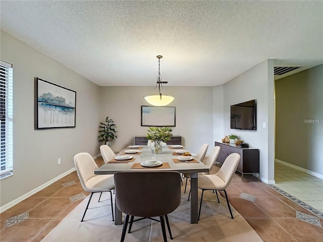 tiled dining space featuring a wealth of natural light and a textured ceiling