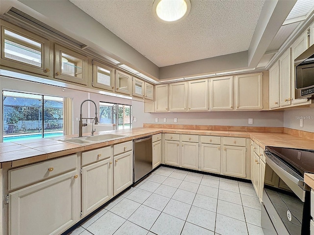 kitchen featuring appliances with stainless steel finishes, sink, a textured ceiling, and light tile patterned floors