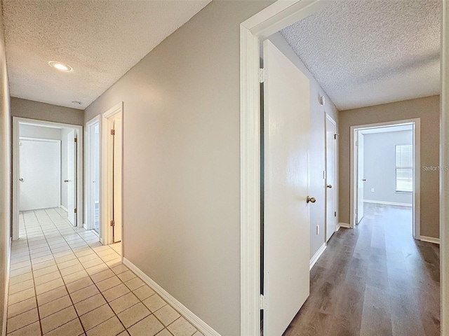 corridor featuring light tile patterned floors and a textured ceiling