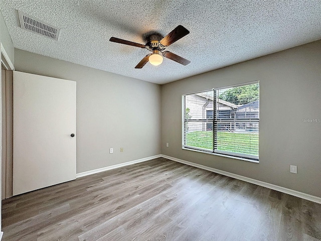 spare room with ceiling fan, light hardwood / wood-style floors, and a textured ceiling