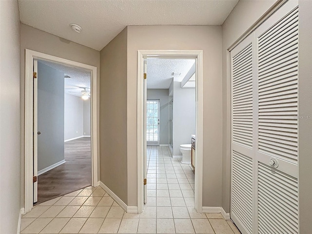 hall featuring light tile patterned floors and a textured ceiling