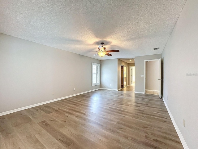 unfurnished room with ceiling fan, wood-type flooring, and a textured ceiling