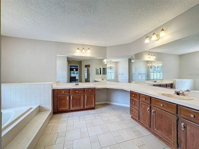 bathroom with tile patterned flooring, vanity, a relaxing tiled tub, a textured ceiling, and an inviting chandelier