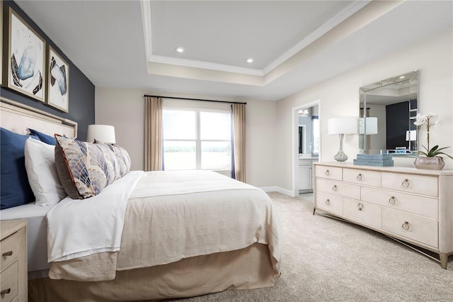 carpeted bedroom featuring ornamental molding, ensuite bathroom, and a raised ceiling