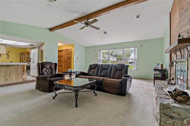 living room with visible vents, lofted ceiling with beams, a textured ceiling, a stone fireplace, and light colored carpet