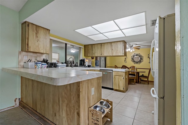 kitchen with a peninsula, light tile patterned flooring, freestanding refrigerator, light countertops, and dishwasher