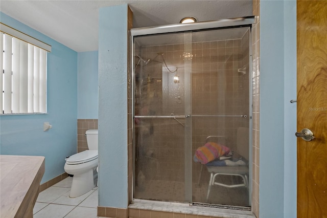 bathroom with vanity, a shower stall, tile patterned floors, toilet, and tile walls