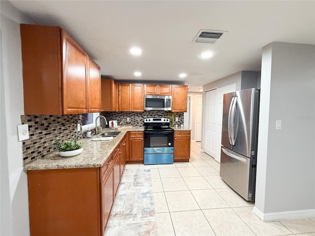 kitchen with tasteful backsplash, light tile patterned flooring, appliances with stainless steel finishes, and sink