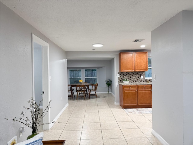 kitchen with light tile patterned flooring, a textured ceiling, and backsplash