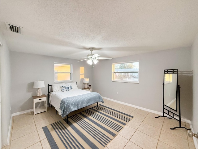 tiled bedroom featuring multiple windows, a textured ceiling, and ceiling fan