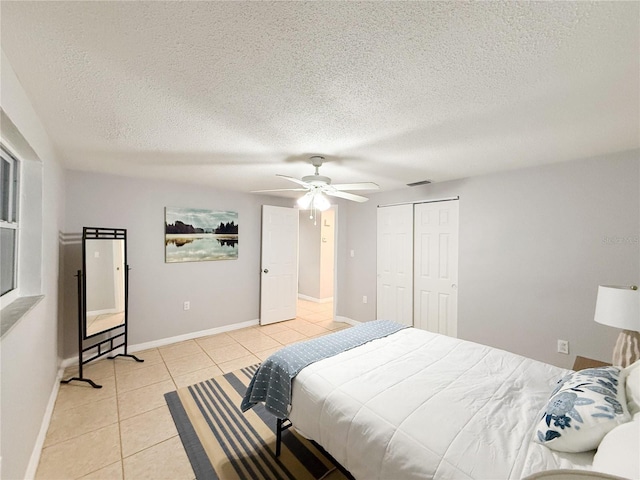 bedroom with a textured ceiling, a closet, ceiling fan, and light tile patterned flooring