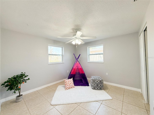 playroom with ceiling fan, plenty of natural light, a textured ceiling, and light tile patterned floors