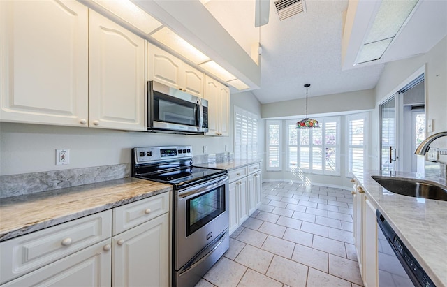 kitchen featuring white cabinetry, sink, hanging light fixtures, light tile patterned floors, and stainless steel appliances