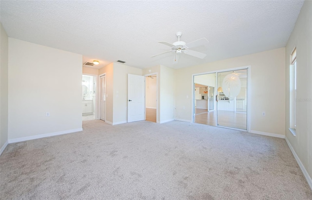 carpeted empty room with ceiling fan and a textured ceiling