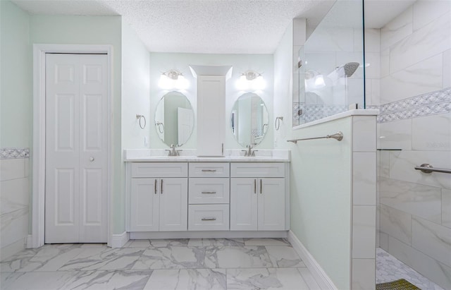 bathroom with vanity, a textured ceiling, and tiled shower