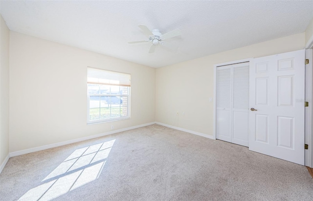 unfurnished bedroom with light carpet, a textured ceiling, a closet, and ceiling fan