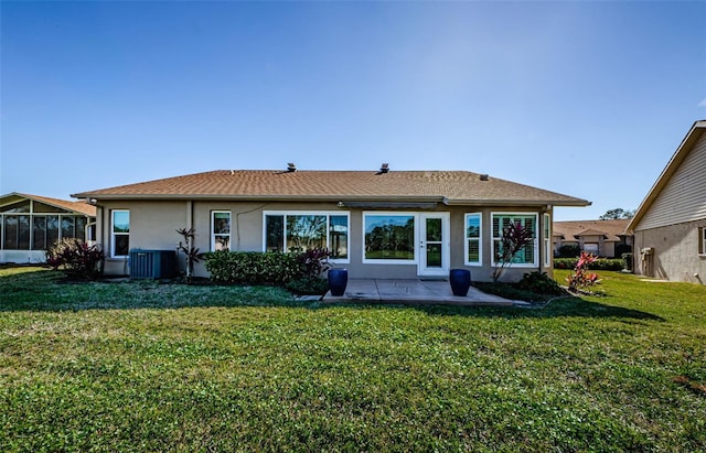 rear view of property featuring a yard, central AC unit, and a patio area