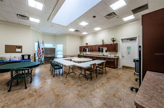 dining space featuring sink, a paneled ceiling, and ornamental molding