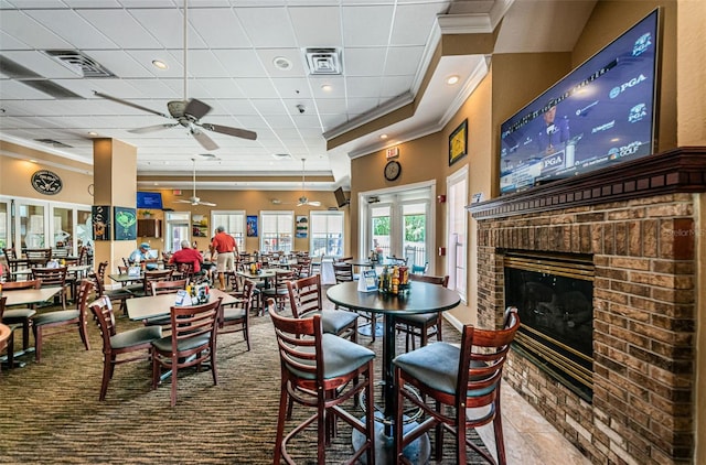 dining area with ceiling fan, a paneled ceiling, ornamental molding, and a brick fireplace