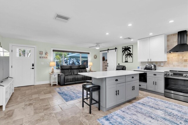 14124 Kulig Ct, Hudson, FL 34667 - kitchen featuring visible vents, decorative backsplash, a barn door, stainless steel range with electric cooktop, and wall chimney exhaust hood