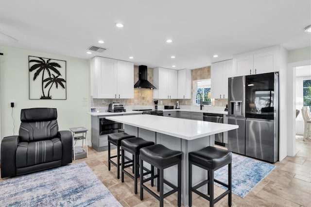 14124 Kulig Ct, Hudson, FL 34667 - kitchen with stainless steel appliances, tasteful backsplash, light countertops, wall chimney range hood, and a kitchen breakfast bar