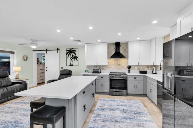 14124 Kulig Ct, Hudson, FL 34667 - kitchen featuring a barn door, gray cabinetry, dishwasher, wall chimney exhaust hood, and stainless steel range with electric stovetop