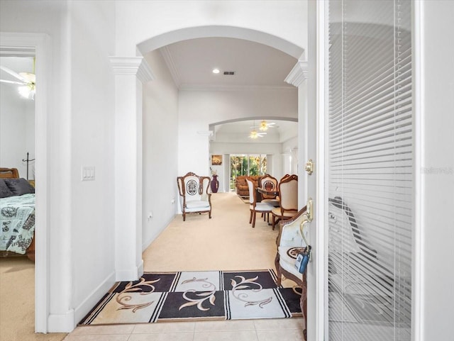 hallway with light tile patterned floors, crown molding, and ornate columns