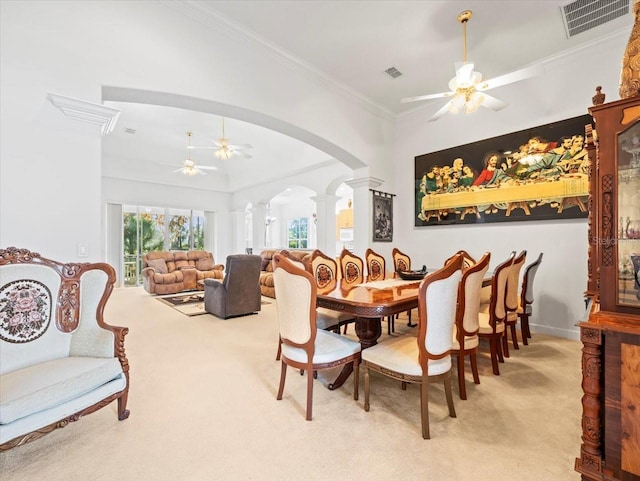 carpeted dining area featuring ornate columns, crown molding, and ceiling fan