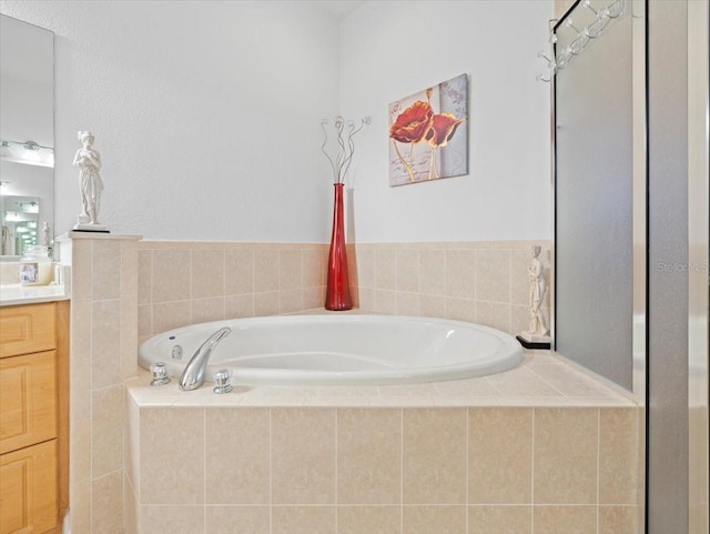 bathroom with vanity and tiled tub