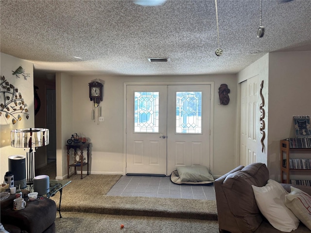 carpeted entrance foyer featuring french doors and a textured ceiling