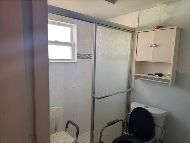 bathroom featuring a shower with door and toilet