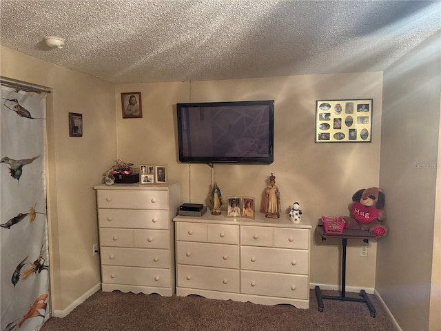 bedroom featuring a textured ceiling and dark colored carpet