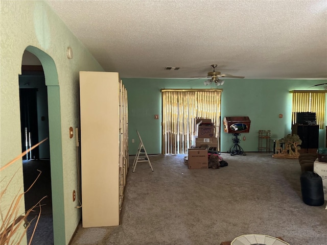 living room featuring ceiling fan, carpet, and a textured ceiling