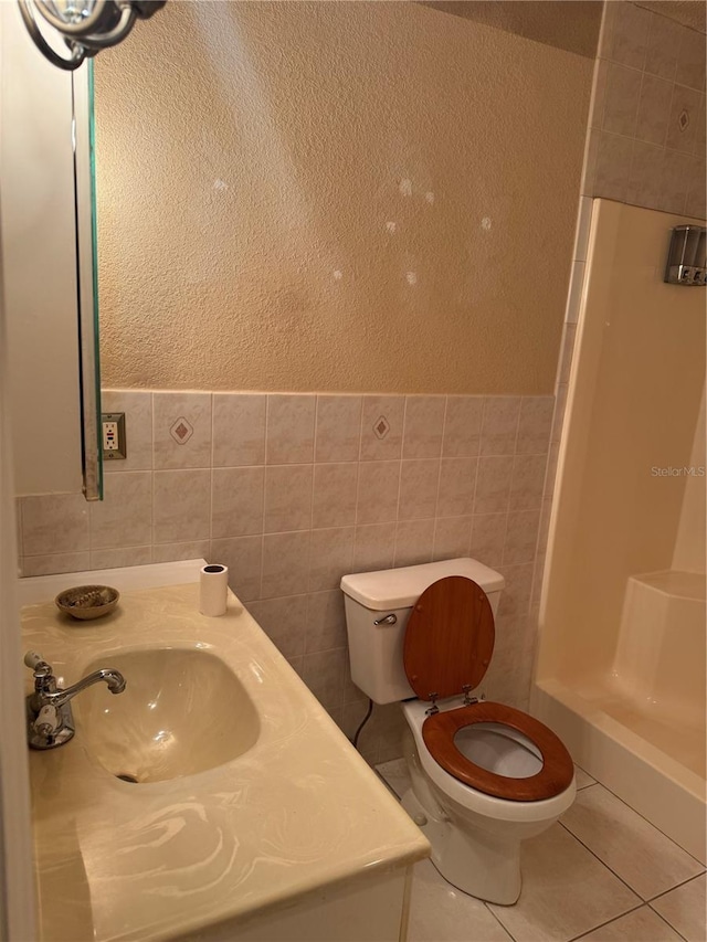 bathroom featuring walk in shower, tile patterned floors, toilet, tile walls, and vanity