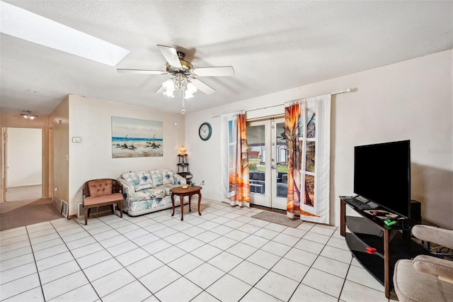 sitting room featuring french doors, a skylight, a textured ceiling, light tile patterned floors, and ceiling fan