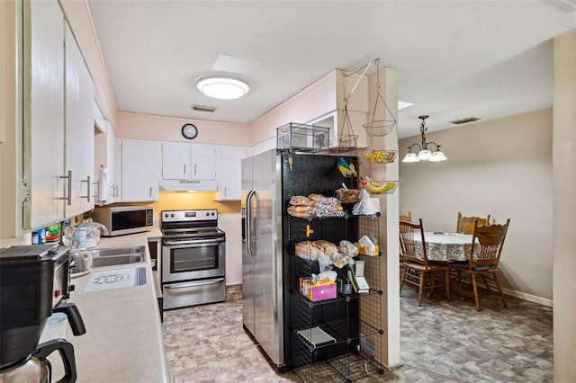 kitchen with pendant lighting, sink, appliances with stainless steel finishes, an inviting chandelier, and white cabinets