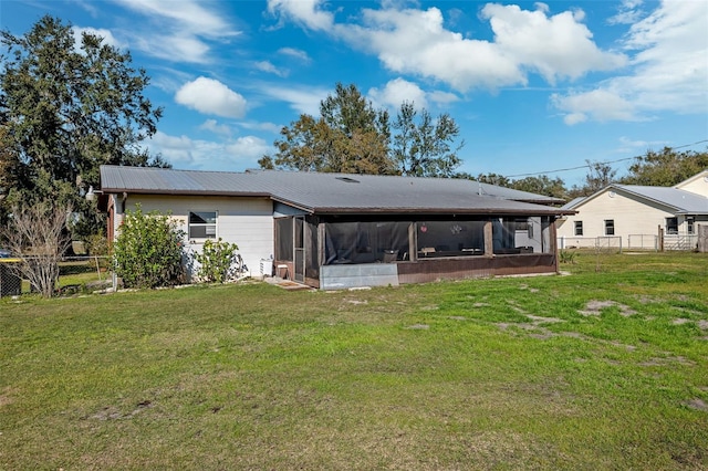 rear view of property featuring a sunroom and a lawn