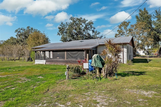 back of property with a lawn and a sunroom