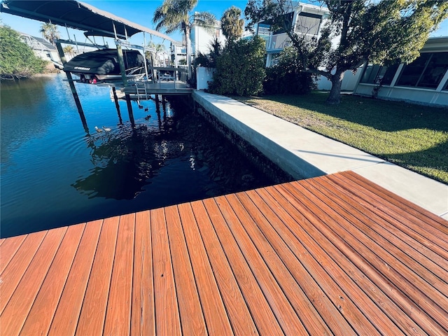 view of dock with a water view and a lawn