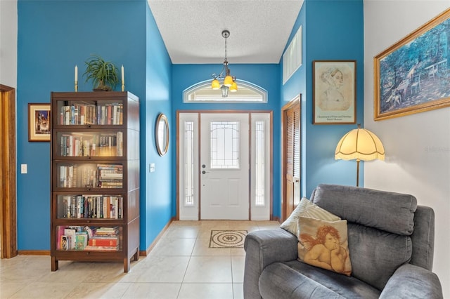 entrance foyer with a towering ceiling, a textured ceiling, and light tile patterned flooring