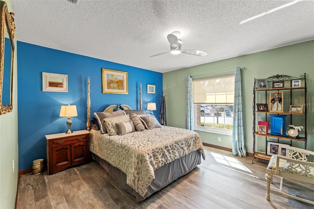 bedroom with ceiling fan, hardwood / wood-style floors, and a textured ceiling