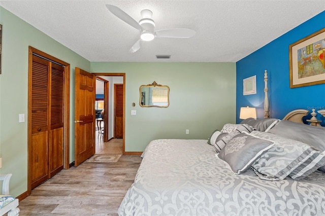 bedroom with light hardwood / wood-style floors, a textured ceiling, ceiling fan, and a closet