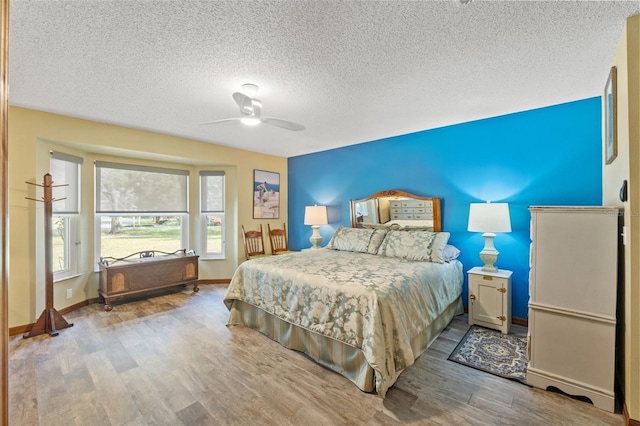 bedroom with a textured ceiling, wood-type flooring, and ceiling fan