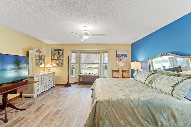 bedroom featuring ceiling fan, light hardwood / wood-style floors, and a textured ceiling